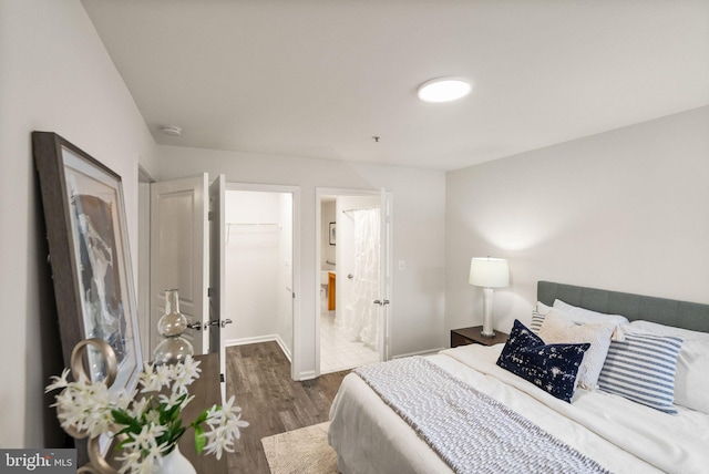 bedroom featuring a closet, dark hardwood / wood-style floors, ensuite bath, and a spacious closet