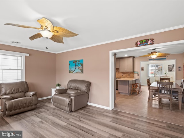 living room with ceiling fan, light hardwood / wood-style flooring, plenty of natural light, and crown molding