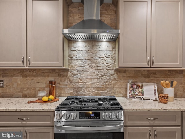 kitchen with wall chimney exhaust hood, gray cabinetry, and stainless steel gas stove