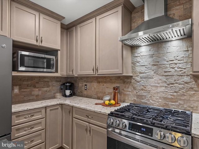 kitchen with light stone countertops, appliances with stainless steel finishes, wall chimney range hood, backsplash, and gray cabinets