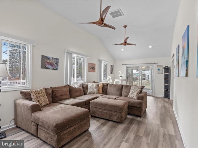 living room with ceiling fan, a healthy amount of sunlight, lofted ceiling, and light hardwood / wood-style floors