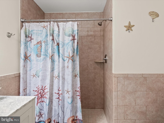 bathroom with tile walls, walk in shower, and vanity