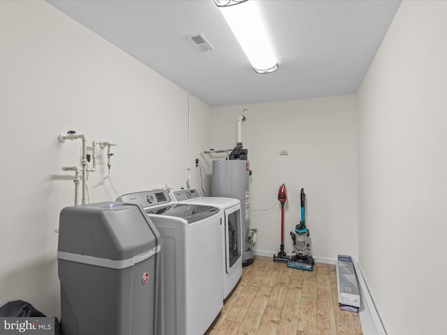 laundry area with water heater, light hardwood / wood-style floors, and independent washer and dryer