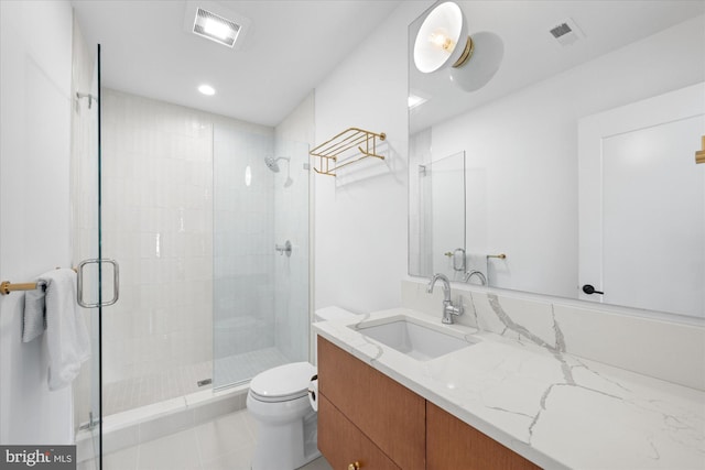 bathroom featuring toilet, a shower with shower door, and vanity