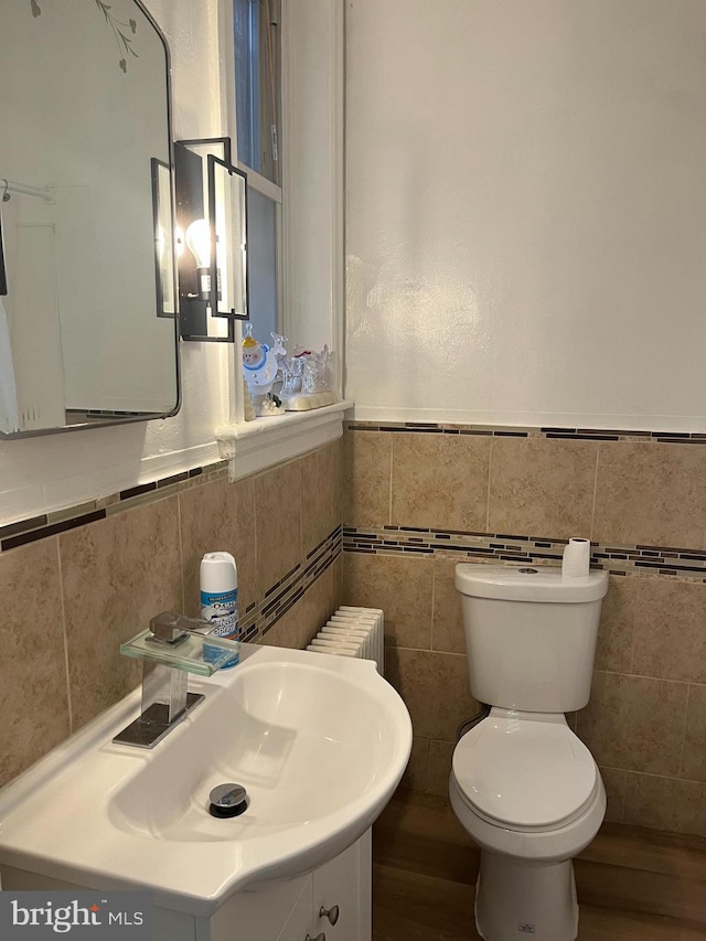 bathroom with wood-type flooring, toilet, vanity, and tile walls