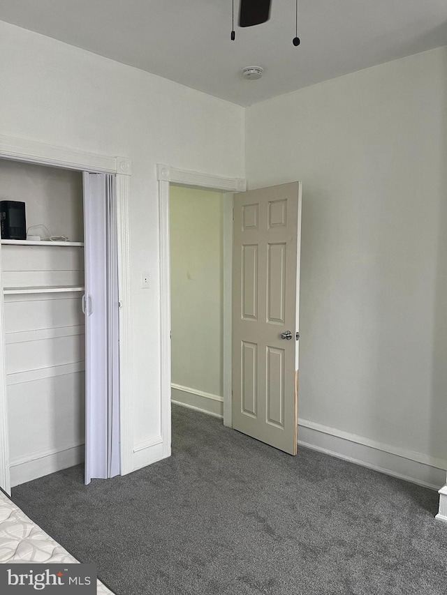 unfurnished bedroom featuring a closet, ceiling fan, and dark colored carpet