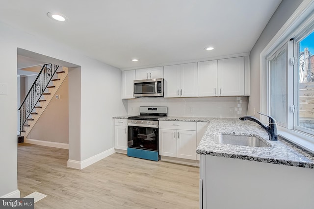 kitchen featuring sink, light wood-type flooring, white cabinets, and appliances with stainless steel finishes