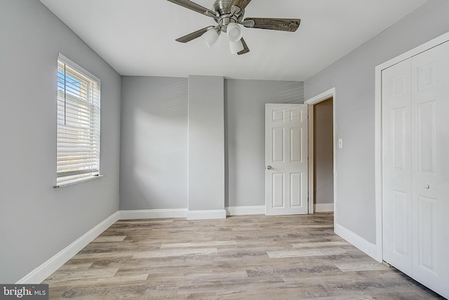 unfurnished bedroom featuring ceiling fan, a closet, and light wood-type flooring