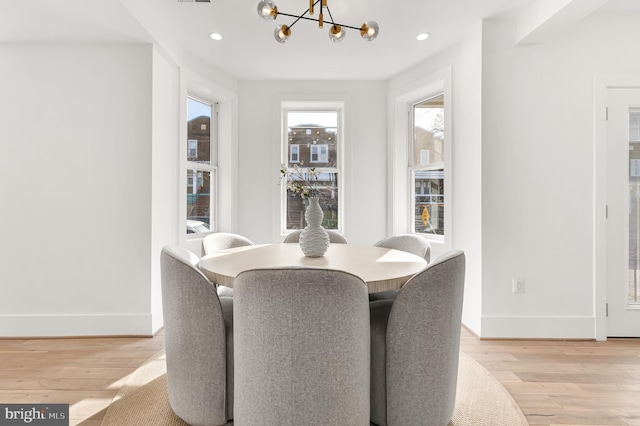 dining space featuring light wood-type flooring and a notable chandelier