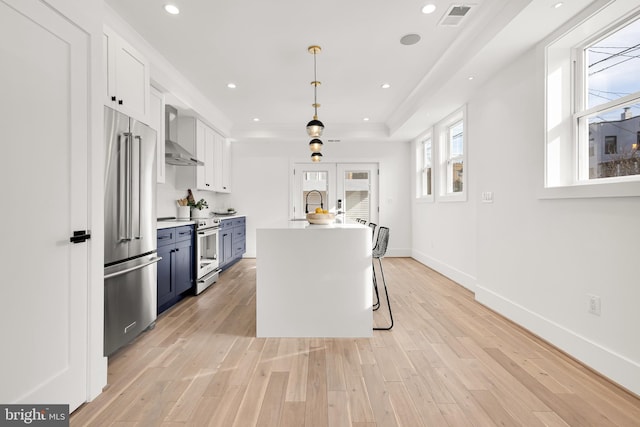 kitchen featuring a kitchen breakfast bar, hanging light fixtures, appliances with stainless steel finishes, white cabinetry, and blue cabinets