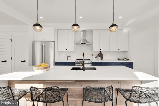 kitchen with wall chimney exhaust hood, white cabinets, a kitchen island with sink, and premium appliances