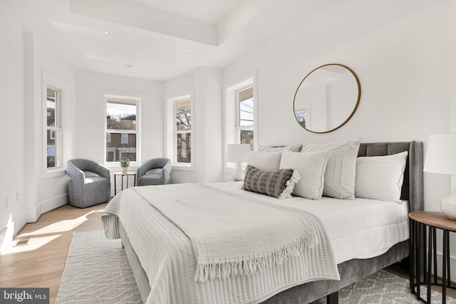 bedroom featuring light wood-type flooring and a tray ceiling