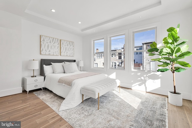 bedroom featuring light hardwood / wood-style floors and a raised ceiling