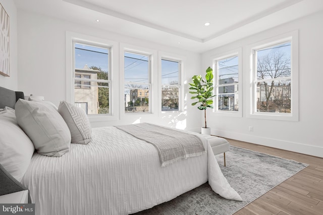 bedroom with hardwood / wood-style flooring and a tray ceiling