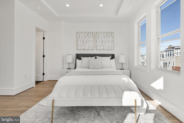 bedroom featuring a raised ceiling and light wood-type flooring