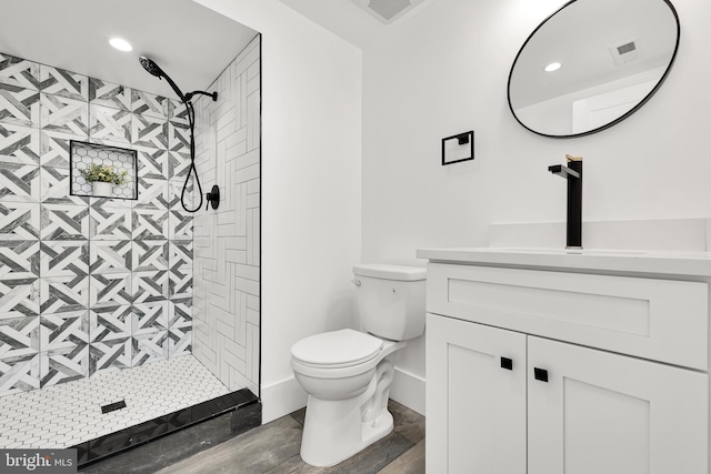 bathroom with vanity, toilet, and a tile shower