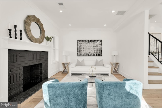 living room featuring light hardwood / wood-style flooring, crown molding, and a fireplace