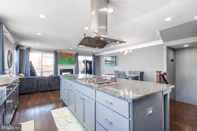 kitchen with stainless steel gas stovetop, dark hardwood / wood-style flooring, island exhaust hood, a center island, and ornamental molding