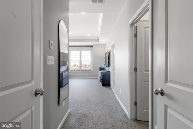 hallway with carpet flooring and a raised ceiling