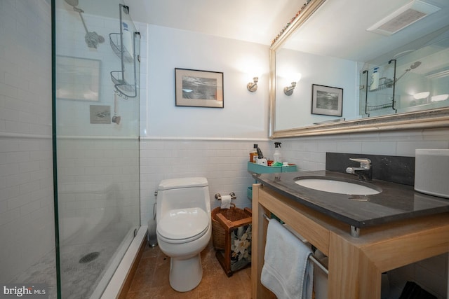 bathroom with a shower with door, tile patterned floors, tile walls, toilet, and vanity