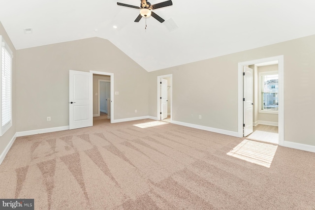 unfurnished bedroom featuring ceiling fan, light colored carpet, multiple windows, and ensuite bathroom