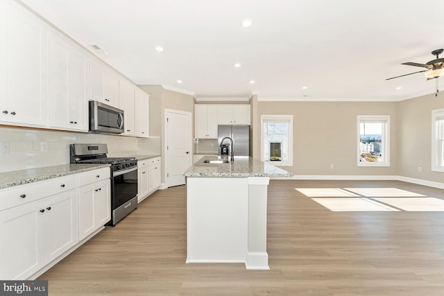 kitchen with light stone countertops, white cabinetry, a kitchen island with sink, and appliances with stainless steel finishes