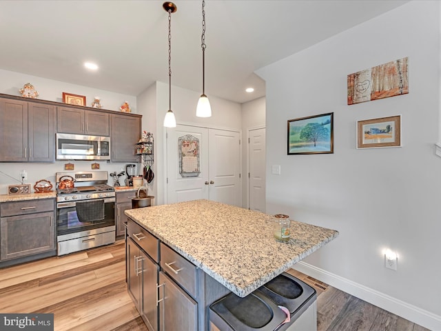 kitchen featuring dark brown cabinetry, a kitchen island, a kitchen bar, stainless steel appliances, and light hardwood / wood-style floors