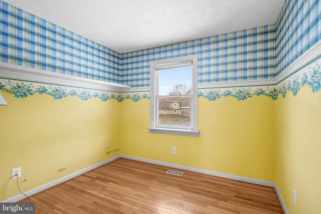 unfurnished room featuring light hardwood / wood-style floors and a textured ceiling