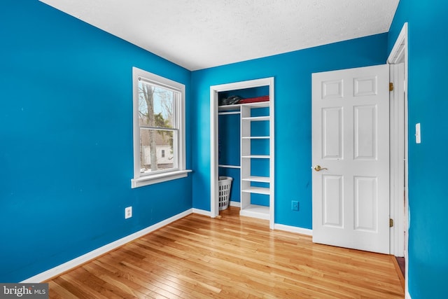 unfurnished bedroom with a closet, light hardwood / wood-style floors, and a textured ceiling