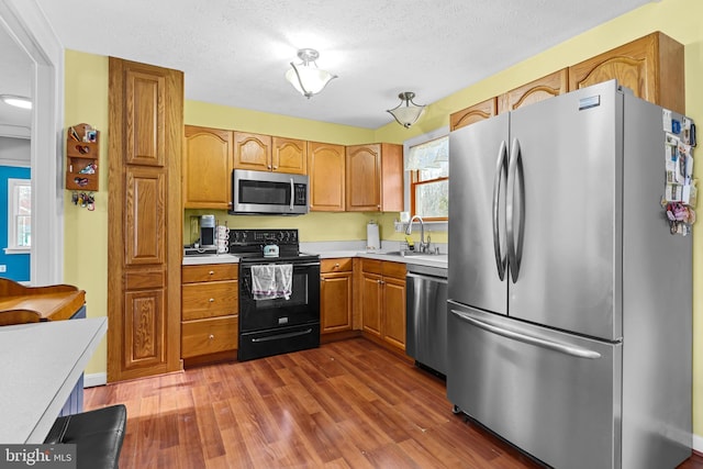 kitchen with dark wood-type flooring, a textured ceiling, sink, and stainless steel appliances