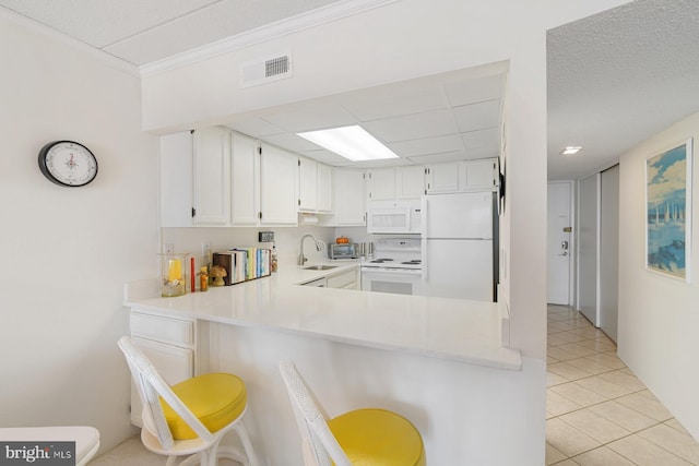 kitchen featuring white appliances, light tile patterned floors, white cabinets, sink, and kitchen peninsula