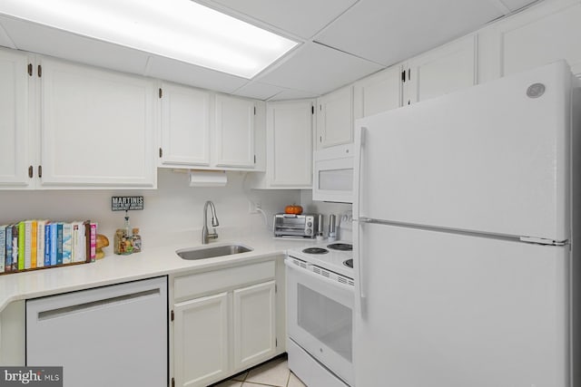 kitchen with white appliances, light tile patterned floors, white cabinets, sink, and a paneled ceiling