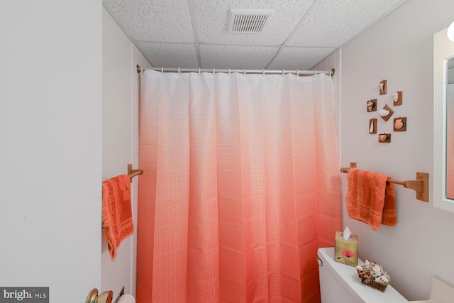 bathroom featuring toilet, a paneled ceiling, and a shower with shower curtain