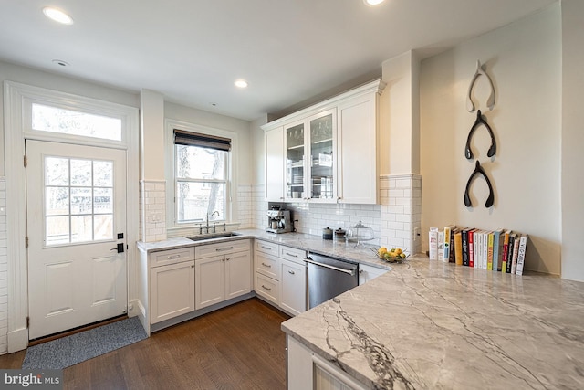 kitchen with sink, dark hardwood / wood-style floors, light stone countertops, white cabinets, and stainless steel dishwasher