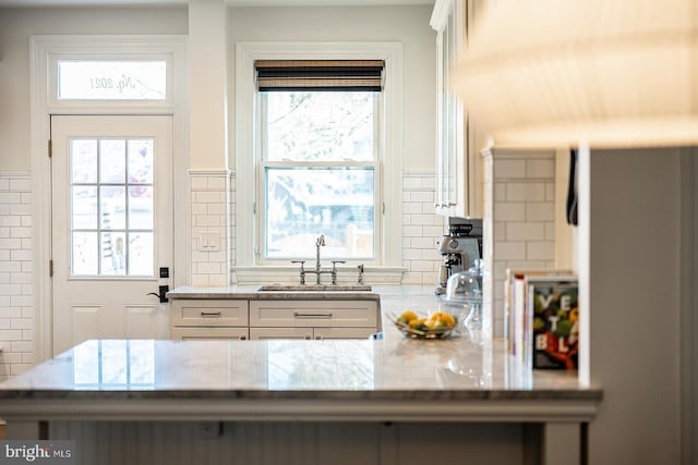 kitchen with white cabinetry, light stone countertops, sink, and kitchen peninsula