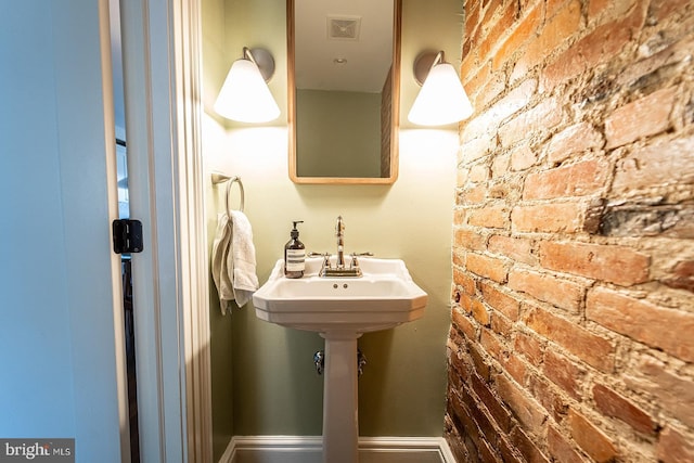 bathroom featuring brick wall