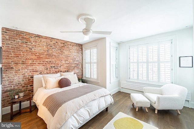 bedroom with ceiling fan, wood-type flooring, a baseboard radiator, and brick wall