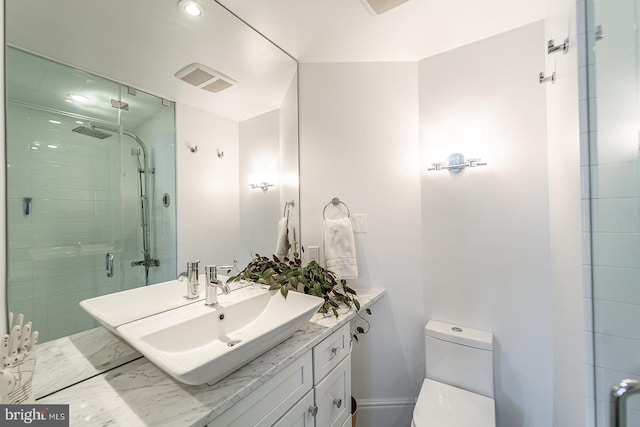 bathroom featuring vanity, toilet, and a shower with shower door