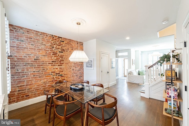 dining room with dark wood-type flooring and brick wall