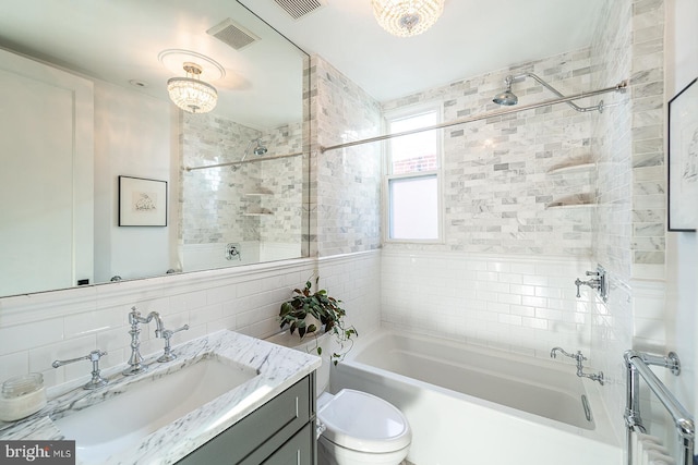 full bathroom featuring tile walls, backsplash, tiled shower / bath combo, vanity, and toilet