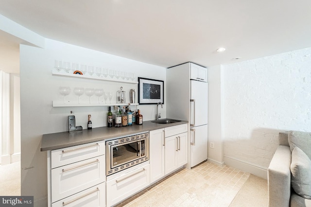 bar featuring white cabinetry, sink, and built in appliances