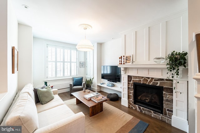 living room with a stone fireplace and dark hardwood / wood-style floors