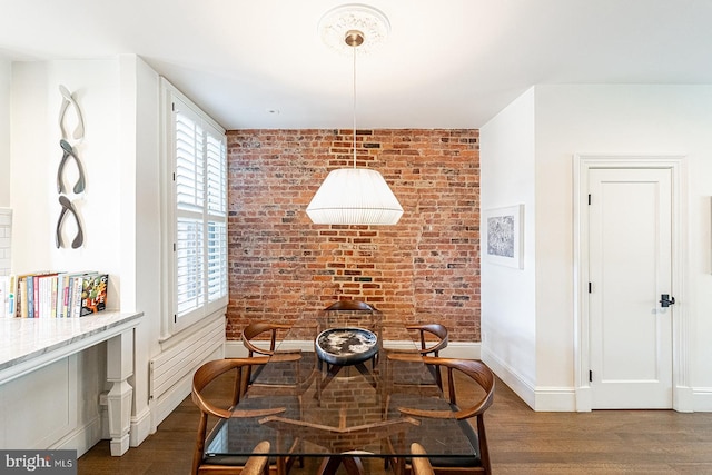 dining space featuring brick wall and dark hardwood / wood-style flooring