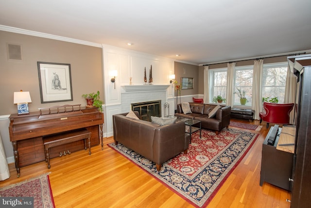 living room with ornamental molding, a fireplace, and light hardwood / wood-style flooring