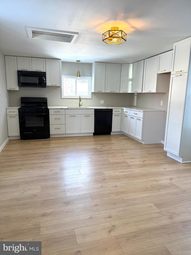 kitchen with black appliances, white cabinetry, and pendant lighting