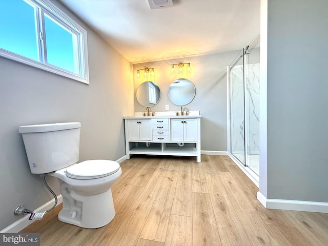 bathroom featuring wood-type flooring, toilet, a shower with door, and vanity