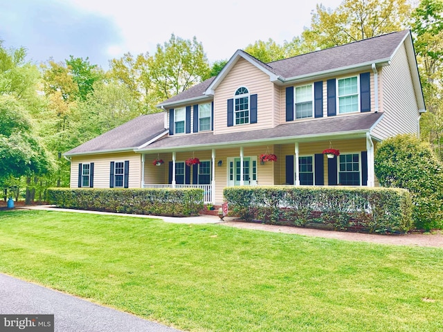 colonial house featuring covered porch and a front yard