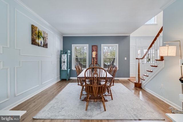 dining space featuring ornamental molding and light hardwood / wood-style flooring