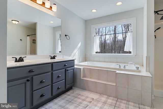 bathroom featuring tiled tub, vanity, and tile patterned flooring