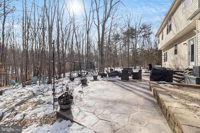 snow covered patio with a trampoline and area for grilling